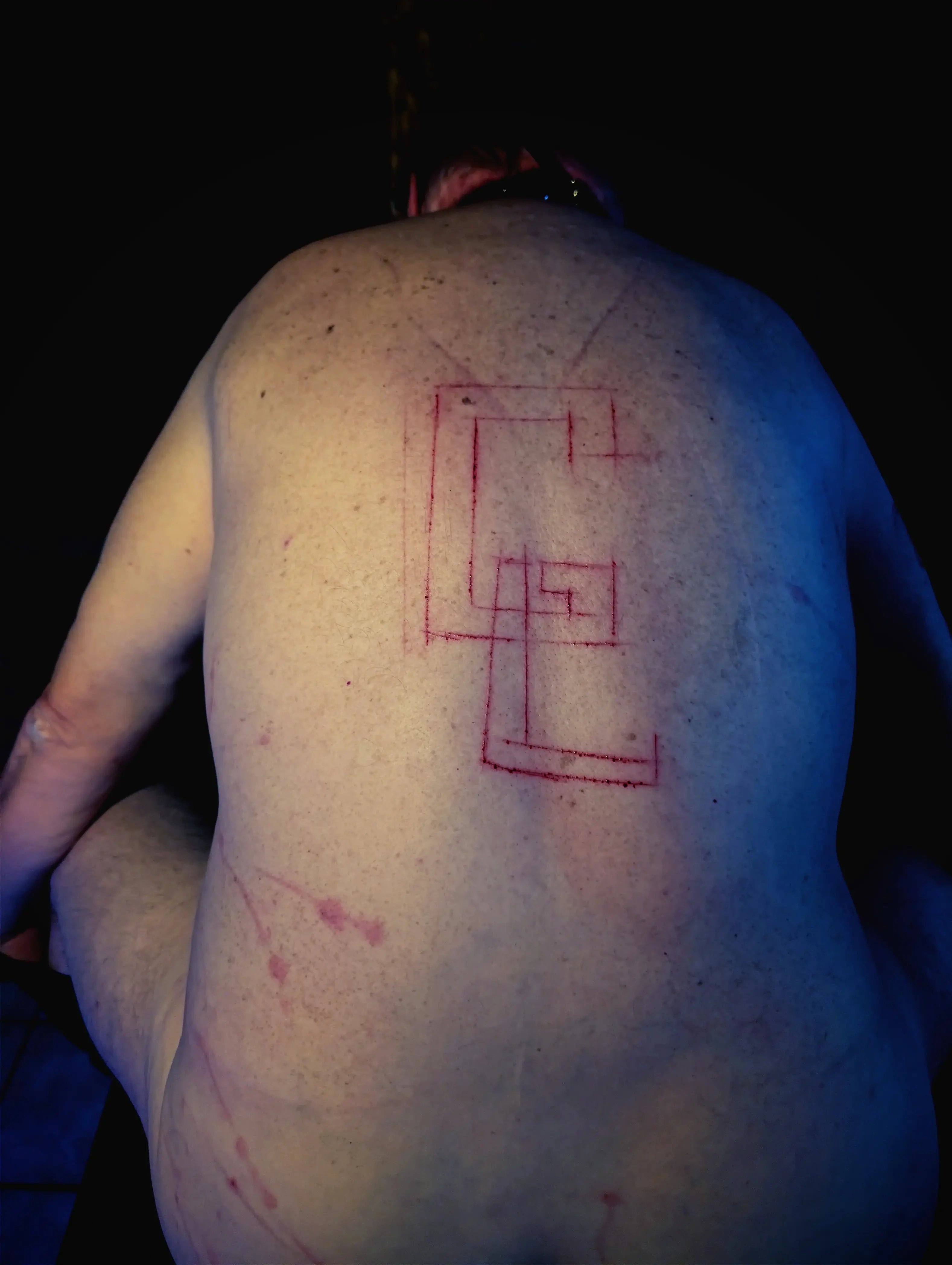 Dos d'un soumis de Gabrielle, les initiales G.L. inscrites au couteau.